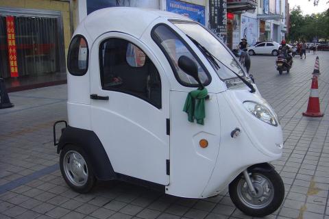 A white three-wheeled car. The Thai for "a white three-wheeled car" is "รถสามล้อสีขาว".