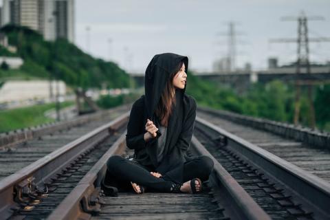 A woman in a hoodie sitting on the railroad. The Thai for "a woman in a hoodie sitting on the railroad" is "ผู้หญิงในเสื้อคลุมมีหมวกนั่งบนทางรถไฟ". A woman in a hoodie sitting on the railroad. The Thai for "a woman in a hoodie sitting on the railroad" is "ผู้หญิงในเสื้อคลุมมีหมวกนั่งบนทางรถไฟ".