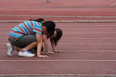 Two girls on a running track. The Thai for "two girls on a running track" is "เด็กผู้หญิงสองคนบนลู่วิ่ง".